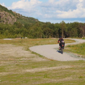 Rusasetvatnet, sykling, aktiviteter hos Austrått agroturisme, en person sykler med barnesete med et barn bakpå langs en gruslagt sykkel- og gangvei