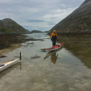 Kajakkpadling, opplevelser med Austrått agroturisme, kajakk ligger i sjøen på grunt vann, en person står ved siden av kajakken