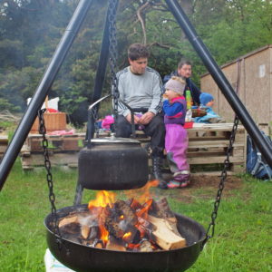 Austrått agrotourism, Austrått CSA, the coffee pot is hanging on the campfire pan while a father and his daughter is enjoying in the background