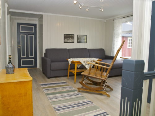 Holiay house, Austrått agrotourism, Kårstua, loft living room, light grey walls, dark grey sofa, brown american rocking chair inthe middle of the photo, a blue door in the background