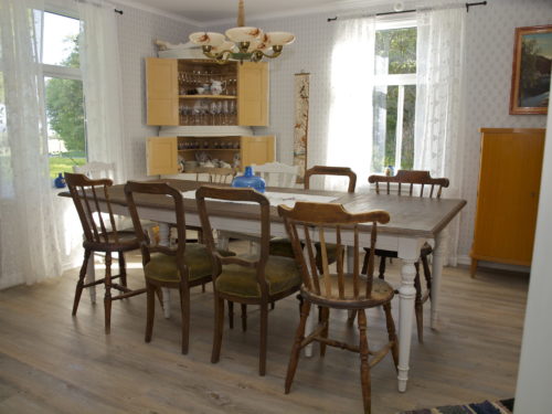 Austrått agroturisme, Kårstua, spisestua, Stort brunt spisebord med hvite bein, hjørneakap, møbler i nostalgisk stil