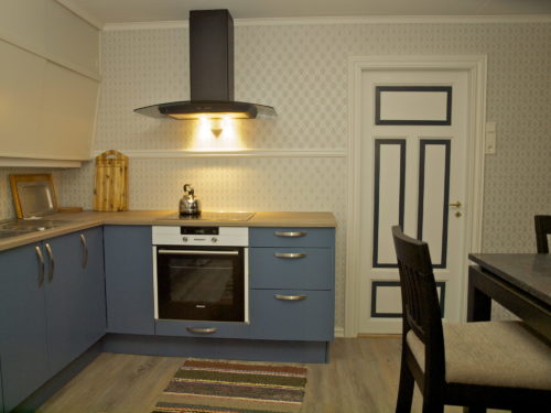 Feriehus, Austrått agroturisme, Kårstua, kjøkken med blå innredning, i midten en komfyr og ventilhette med lys