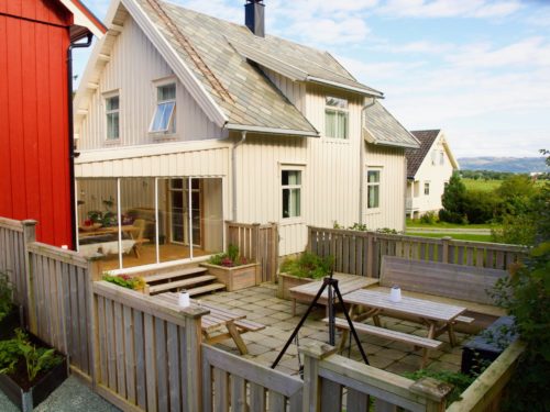 Ørland, Austrått agroturisme, i forgrunnen en utplass med bord, benker og bålpanne, hvitt hus bak.