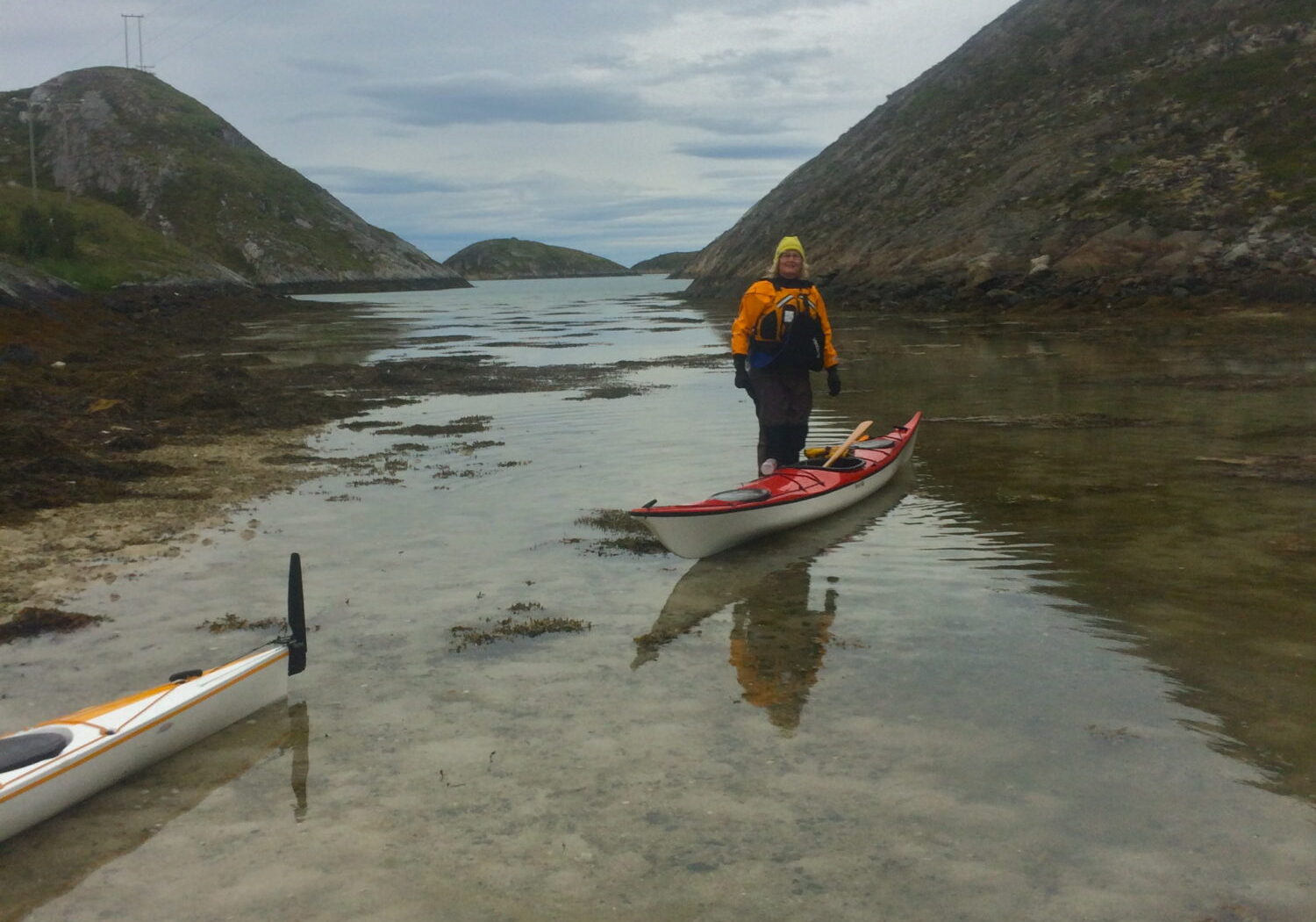 Kajakkpadling, opplevelser med Austrått agroturisme, kajakk ligger i sjøen på grunt vann, en person står ved siden av kajakken